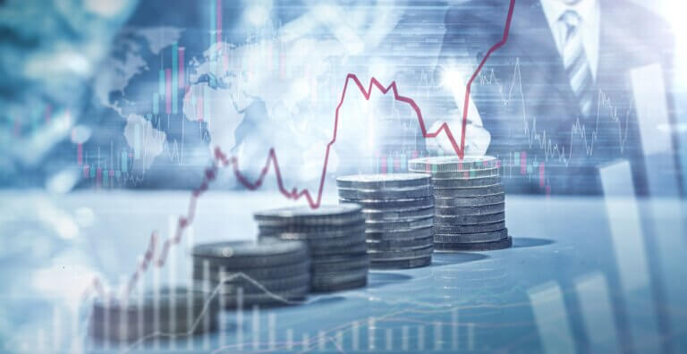 mehrere Münzstapel mit steigender Größe über die eine rote Linie verläuft, die einen Aktienkurs repräsentieren soll