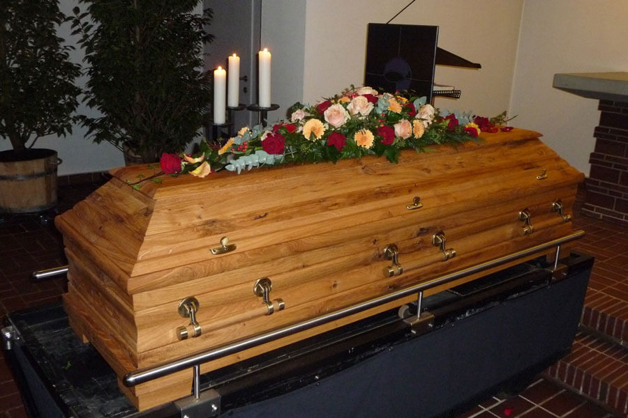Bestattungsvorsorge Bad Oeynhausen | Hölzener Sarg mit roten und apricotfarbenen Rosen