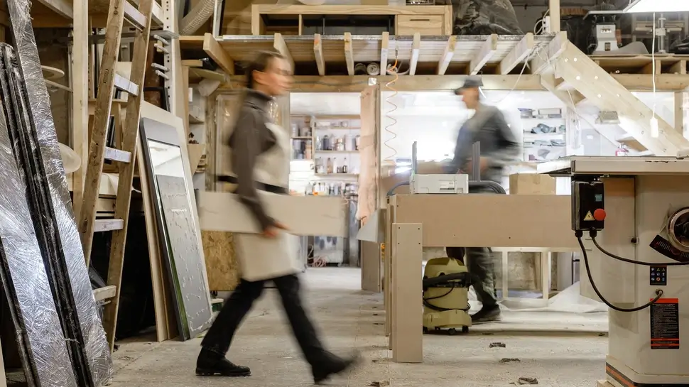 Exposure photography two unidentified young employees of small woodworking and furniture industry working on new furniture collection. Concept of own small successful production