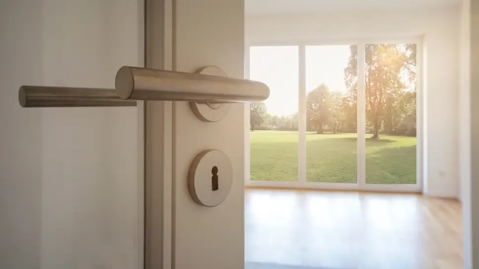 Neubau-Immobilie Umzug in neue Wohnung - Tür in modernes Wohnzimmer mit Blick auf Garten Fenster und Türen Oldenburg | Nahaufnahme Türklinke im Hintergrund Bodentiefe Fenster