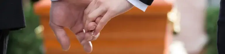 Bestattungsvorsorge Großenkneten | sich haltende Hände vor Sarg bei Trauerfeier