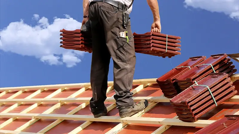 Dachsanierung Gronau Dachsanierung Gronau | Dachdecker trägt Dachziegel