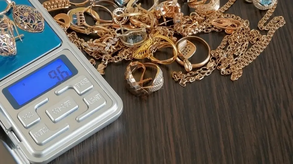 Pawnshop concept, composition with jewelry scales and a lot of gold jewelry on black wooden background with copy space, top view, Goldankauf | Schmuck wird gewogen