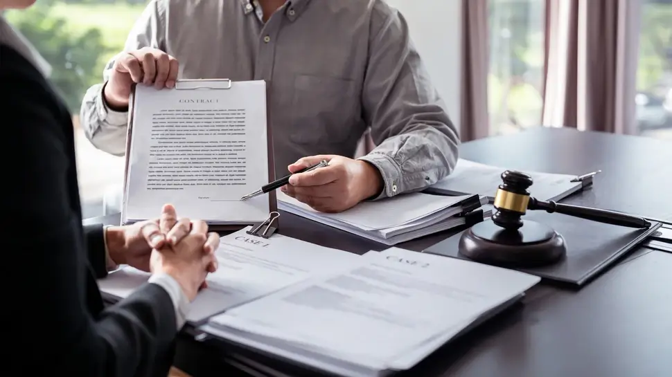 Male lawyer showing contract and pointing the signature box for signing while explaining and consultation about legislation agreement and terms data of business contract to businessman in law firm Fachanwalt für Arbeitsrecht Münster | Vertrag zwischen Anwalt und Mandant zur Unterschrift