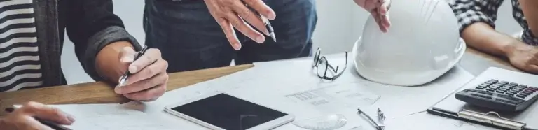 Ingenieurbüro Gera | Planbesprechung am Tisch mit verschiedenen Gegenständen und Bauunterlagen