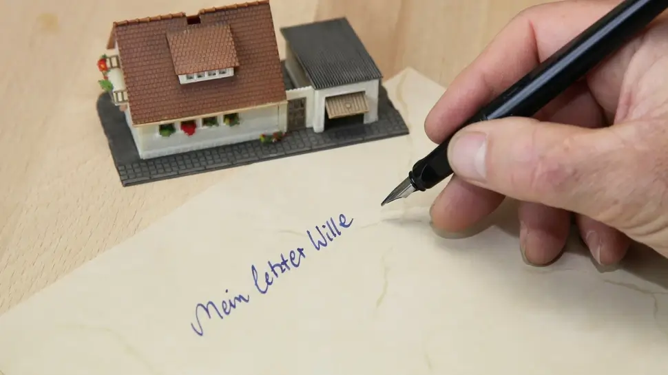 Testament Bestattungsvorsorge Großenkneten | Hand mit Füller, "Mein letzter Wille", kleines Modell-Haus