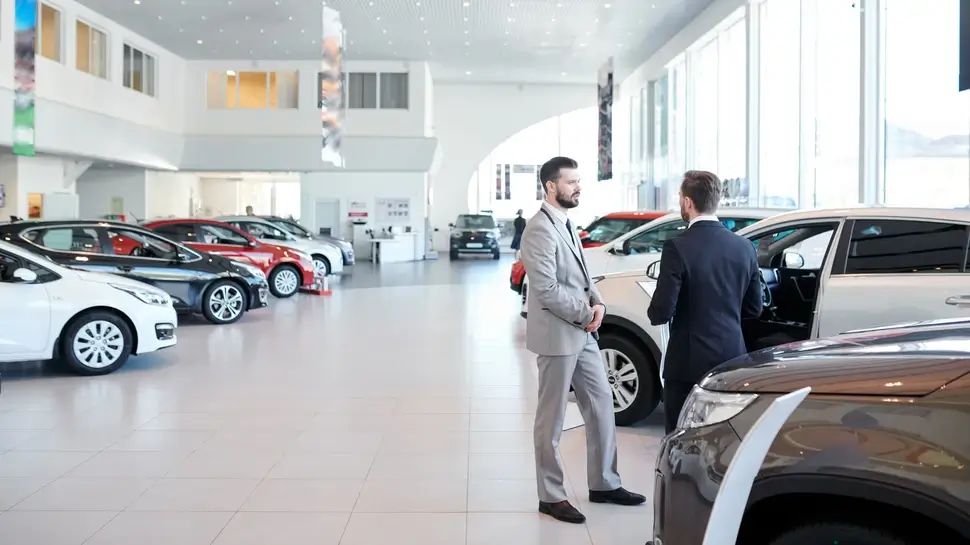 Professional salesperson selling new cars in a modern auto salon. Two men standing and choosing a new car Autohaus in Naumburg | Beratung