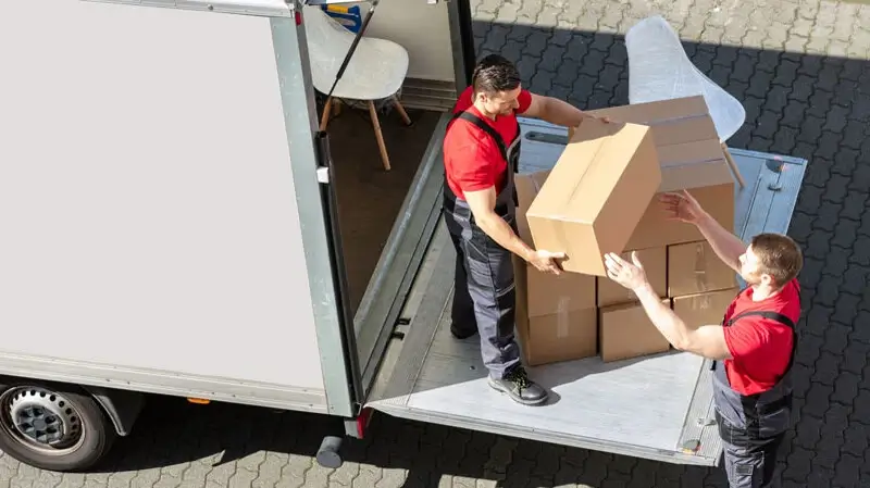 Umzug Bundeswehrumzug | Umzugskarton wird von einem Arbeiter zum anderen gereicht. Zu sehen sind weitere Kartons auf Heckklappe eines Transporters