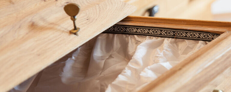 Bestattungsvorsorge Lübbecke | Ein offener Sarg, bei dem der Deckel aufliegt, sodass man reinsehen kann