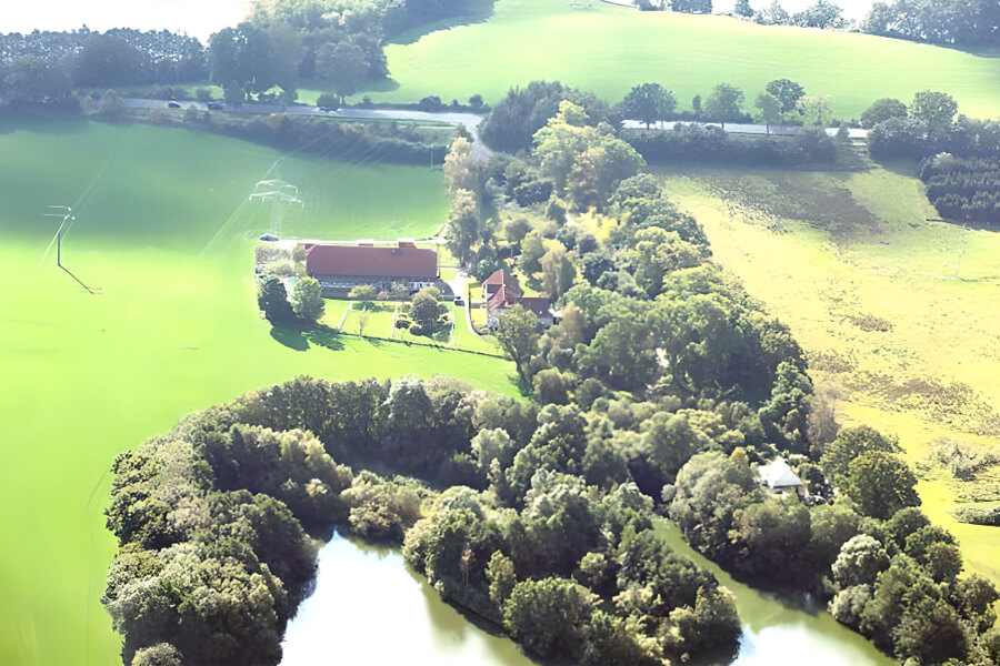 Resthof kaufen in Schleswig Holstein | Luftaufname eines Resthofs mit grünem, weitläufigem Grundstück