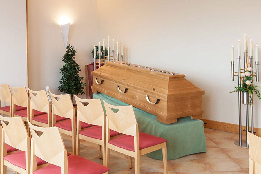 Bestattungsvorsorge Lübbecke | Eigener Abschiedsraum von Brauns Bestattungen mit Stühlen, Kerzen, Beleuchtung und einem Sarg
