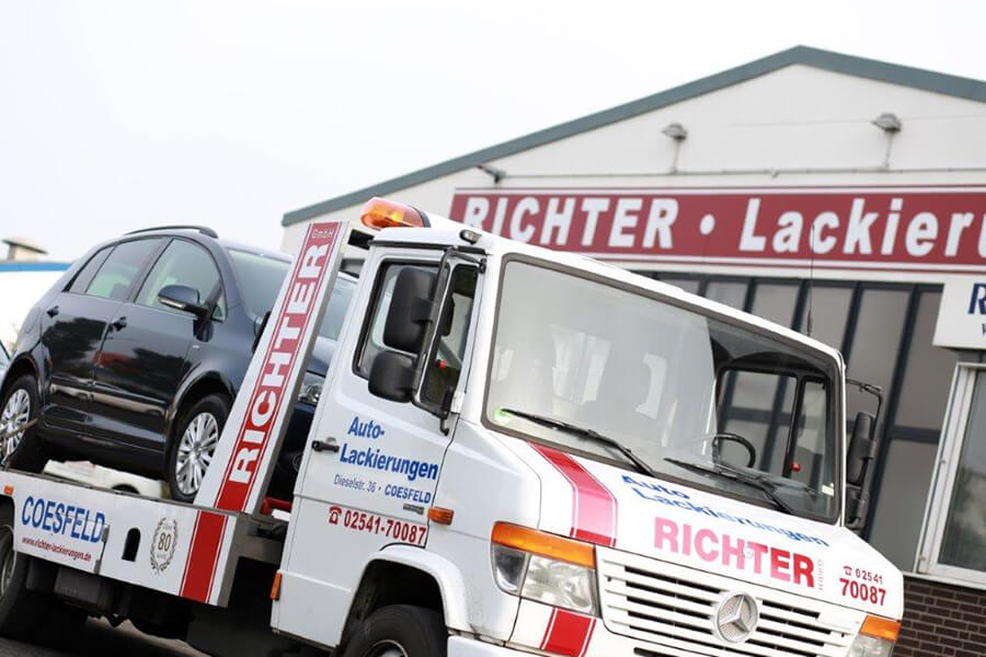 Unfallinstandsetzung von Fahrzeugen und Fahrzeuglackierungen in Coesfeld | Abschleppwagen mit Auto auf der Ladefläche vor der Richter Lackierungen GmbH