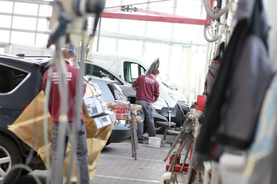 Unfallinstandsetzung von Fahrzeugen und Fahrzeuglackierungen in Coesfeld | Aufnahme aus der Garage der Richter Lackierungen GmbH mit zwei arbeitenden Mitarbeitern
