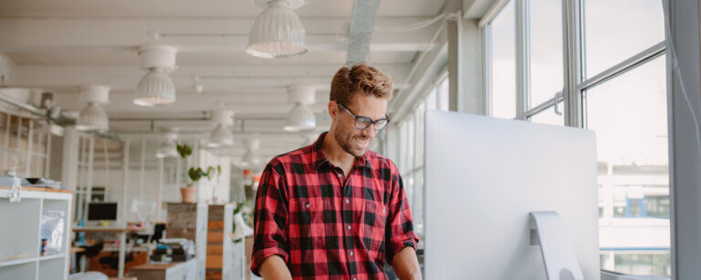 Webdesigner arbeitet stehend am Computer