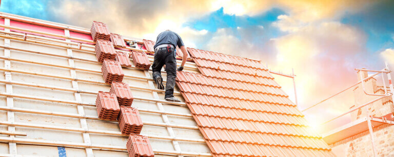 Dachdecker Hamburg | Dachdecker arbeitet an der Verlegung roter Ziegel auf einem Neubau
