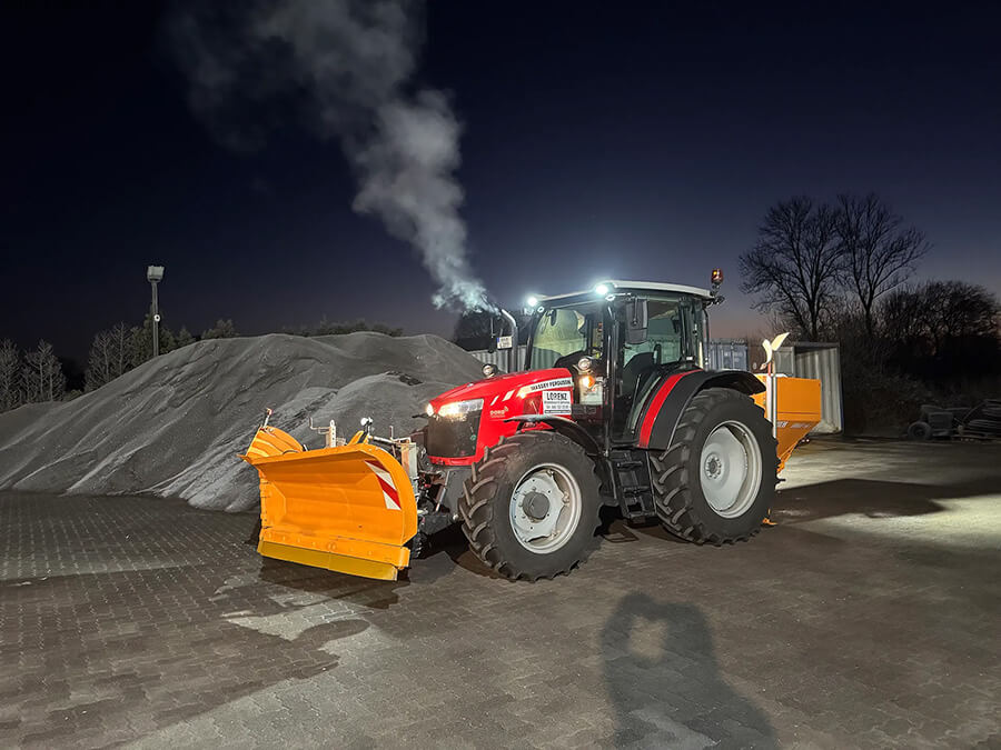 Winterdienst Hamburg | Ein leistungsstarker Traktor mit Schneepflug bereitet Streumaterial für den Winterdienst vor und sorgt für sichere Straßen bei frostigen Temperaturen.