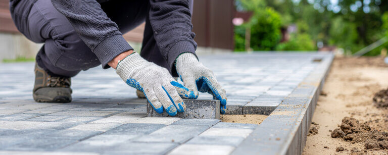Maurer und Betonarbeiten, Fliesenleger Winsen (Luhe) | Handwerker verlegt Pflastersteine für einen ebenen und stabilen Untergrund