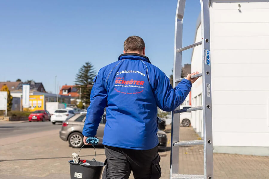Büroreinigung Hildesheim | Mitarbeiter der Albert Schröter Gebäudeservice GmbH trägt Eimer und Leiter für Reinigungsarbeiten