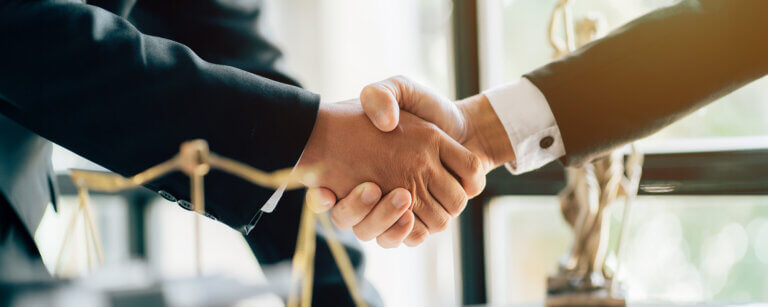 Arbeitsrecht und Kündigungsschutz in Göttingen | Ein Handschlag vor juristischen Symbolen – erfolgreich verhandelte Abfindungen und Einigungen durch erfahrene Anwälte in Göttingen