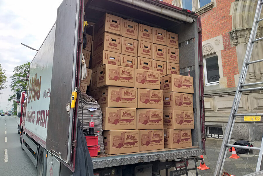 Umzüge in Wilhelmshaven | Zwei Umzugsfahrzeuge der Willms Spedition vor einem historischen Gebäude, bereit für einen reibungslosen Privatumzug