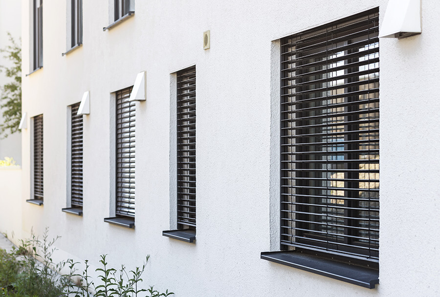 Rollladen Hannover | Außenliegende Raffstores an einer modernen Hausfassade bieten flexiblen Sonnen- und Sichtschutz und schützen die Innenräume effektiv vor Hitze
