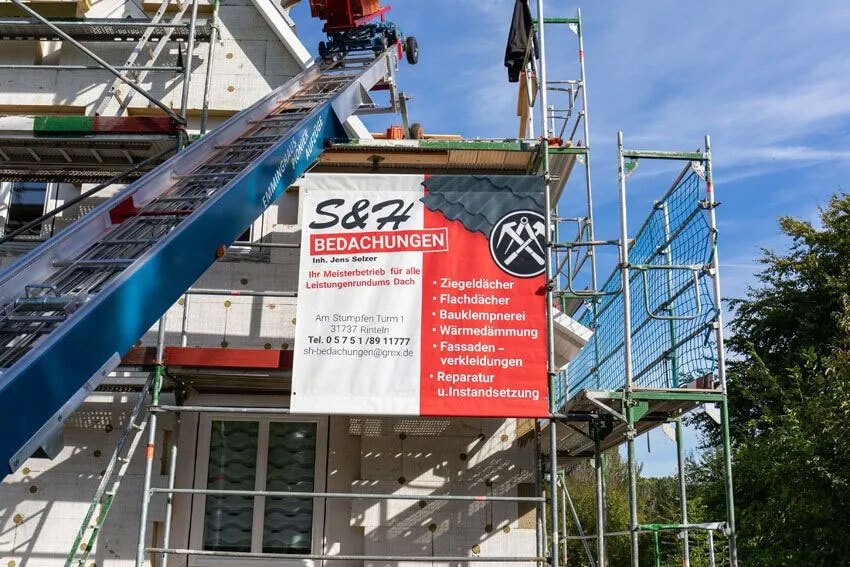 Flach- und Steildachsanierung Rinteln | Firmenbanner von S&H Bedachungen an einer Baustelle