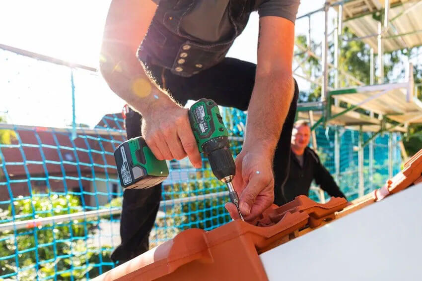 Fassadenarbeiten und Bauklempnerei Rinteln | Präzise Verschraubung der Firstziegel sorgt für einen sicheren Halt und schützt das Dach langfristig vor Wind und Wetter