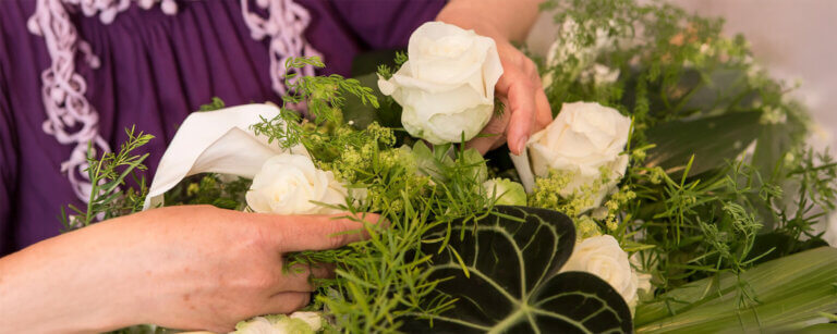 Bestattungsvorsorge für Barmstedt und Umgebung | Weiße Rosen werden zu einem Trauergesteck gebunden